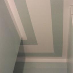 Gregor - Fragment ściany i sufitu z geometrycznym wzorem w odcieniach bieli i błękitu, z widocznym fragmentem białej listwy przysufitowej.