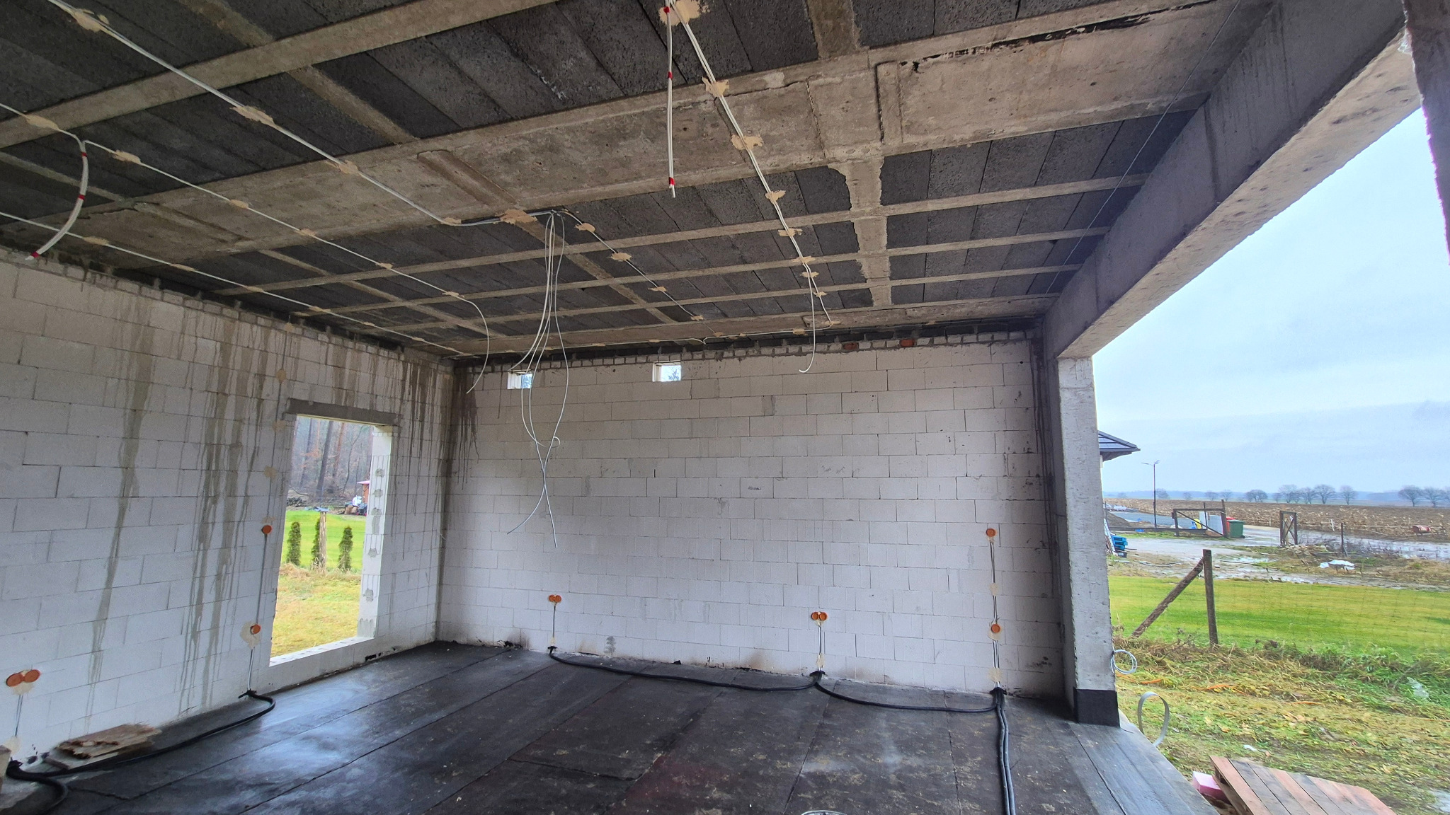 Instalacja elektryczna w surowym budynku ze ścianami z betonu komórkowego w Swarzędzu. Widoczne kable i puszki elektryczne.