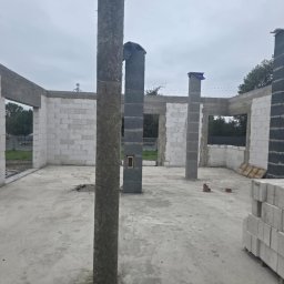 PRODOM MARCIN KOŁAT - Surowy stan domu z białych bloczków: widoczne filary, ściany w trakcie budowy, surowy beton na podłodze. Etap wznoszenia konstrukcji budynku.