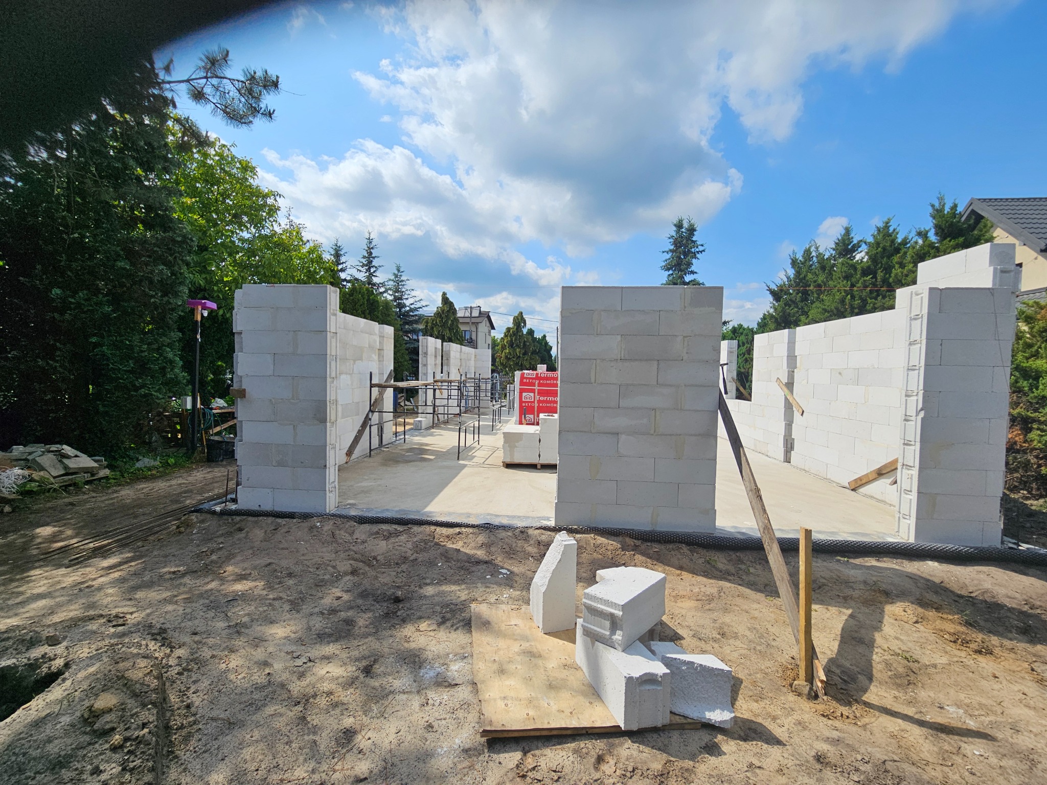 Stan surowy otwarty domu z betonu komórkowego w Zawierciu, ściany z bloczków, widoczne zbrojenia i elementy konstrukcyjne. Budowa w toku, słoneczny dzień.