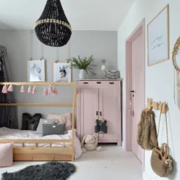 Pok&oacute;j dziecięcy w pastelowych barwach: drewniane ł&oacute;żko z baldachimem, r&oacute;żowa szafa, drzwi w kolorze pudrowego r&oacute;żu i zieleni. Dodatki: lampa z koralik&oacute;w, makrama.