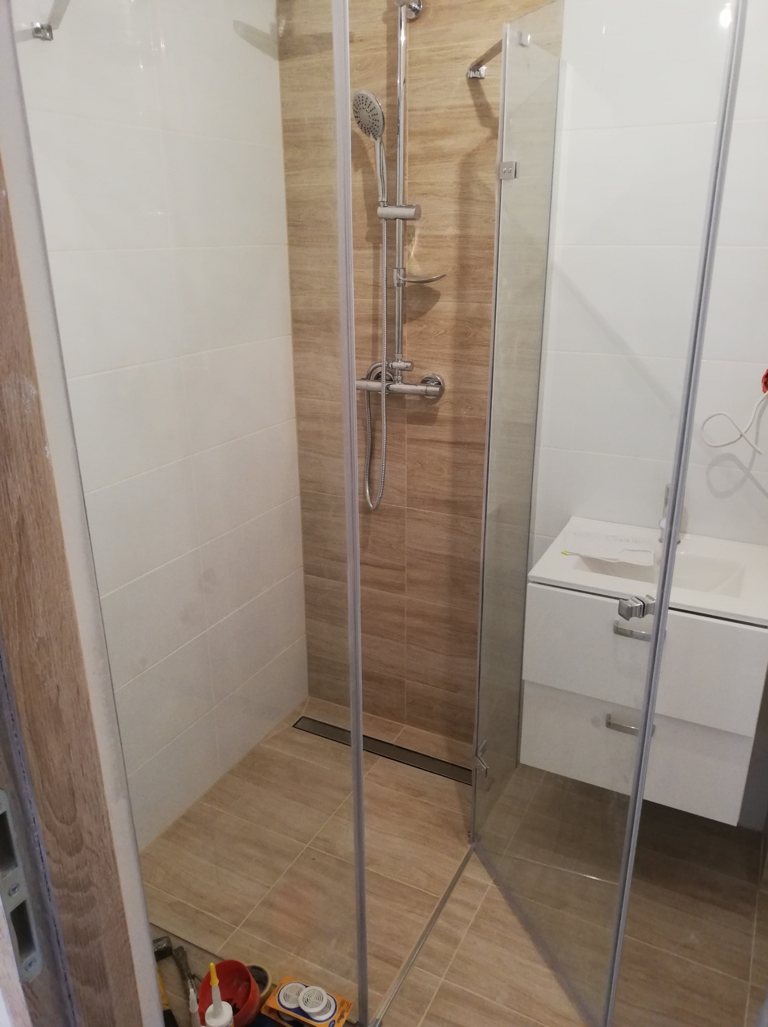 Nowoczesna kabina prysznicowa z odpływem liniowym w wyremontowanej łazience w Gliwicach, widoczne narzędzia i materiały budowlane na podłodze.