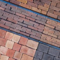 Grupa IVY Spółka z o.o. - Ekspozycja różnokolorowych kostek brukowych w Górze, prezentująca różne wzory ułożenia i faktury.