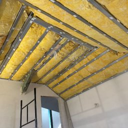 Usługi minikoparką Edengard Andrzej Folwarski - Poddasze w trakcie ocieplania wełną mineralną, widoczne metalowe profile konstrukcyjne, fragment ściany i rusztowania