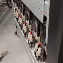 Wnętrze szafy UPS z widocznymi akumulatorami i złączami, częściowo zdemontowana obudowa.