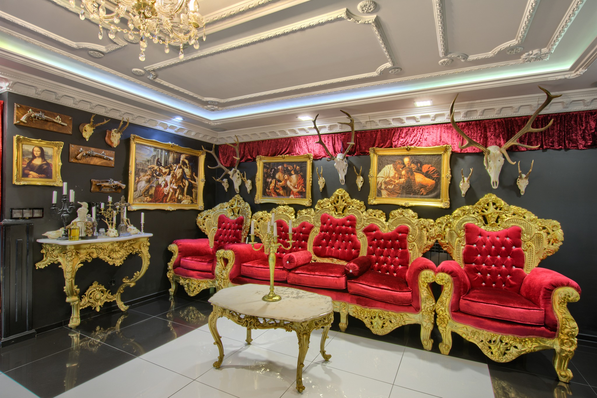 Bogato zdobione wnętrze w Kołobrzegu: czerwone, aksamitne fotele z pozłacanymi ramami, marmurowy stolik i ściany udekorowane obrazami w złotych ramach i trofeami myśliwskimi.