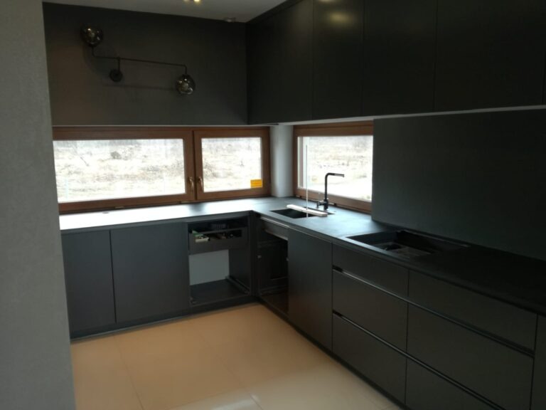 Nowoczesna, ciemna kuchnia z kamiennym blatem, widoczne okno z drewnianą ramą i oryginalne oświetlenie sufitowe.