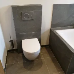 Nowoczesna łazienka z podwieszaną toaletą, szarą glazurą imitującą kamień i chromowanym szczotką do WC