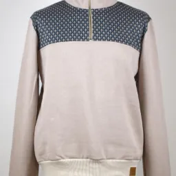 Beżowa bluza z krótkim suwakiem i geometrycznym wzorem na ramionach, prezentowana na manekinie na jasnym tle.