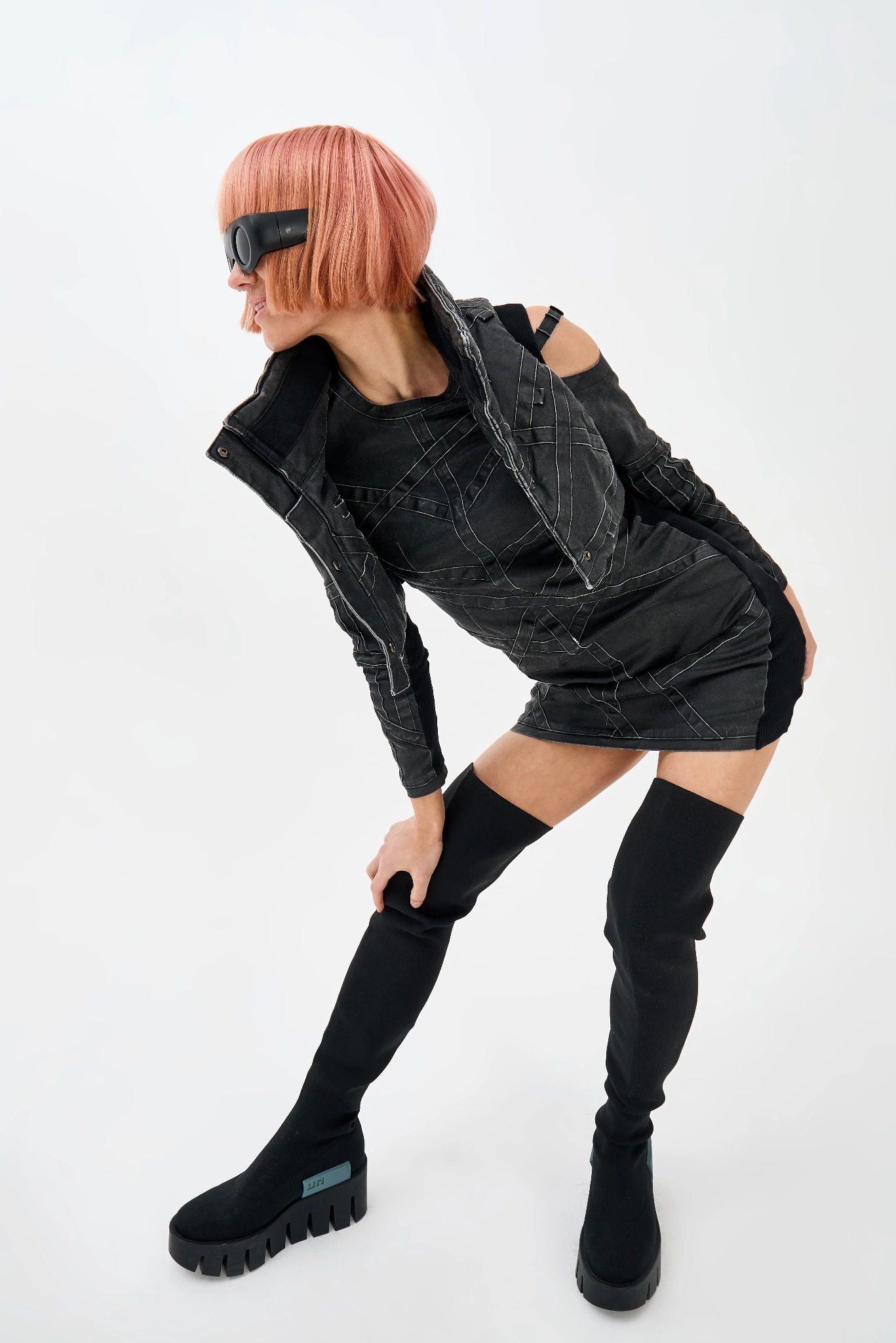 Modelka w Gubinie prezentuje awangardową stylizację: czarna sukienka z geometrycznym wzorem, wysokie skarpeto-buty na platformie i futurystyczne okulary.
