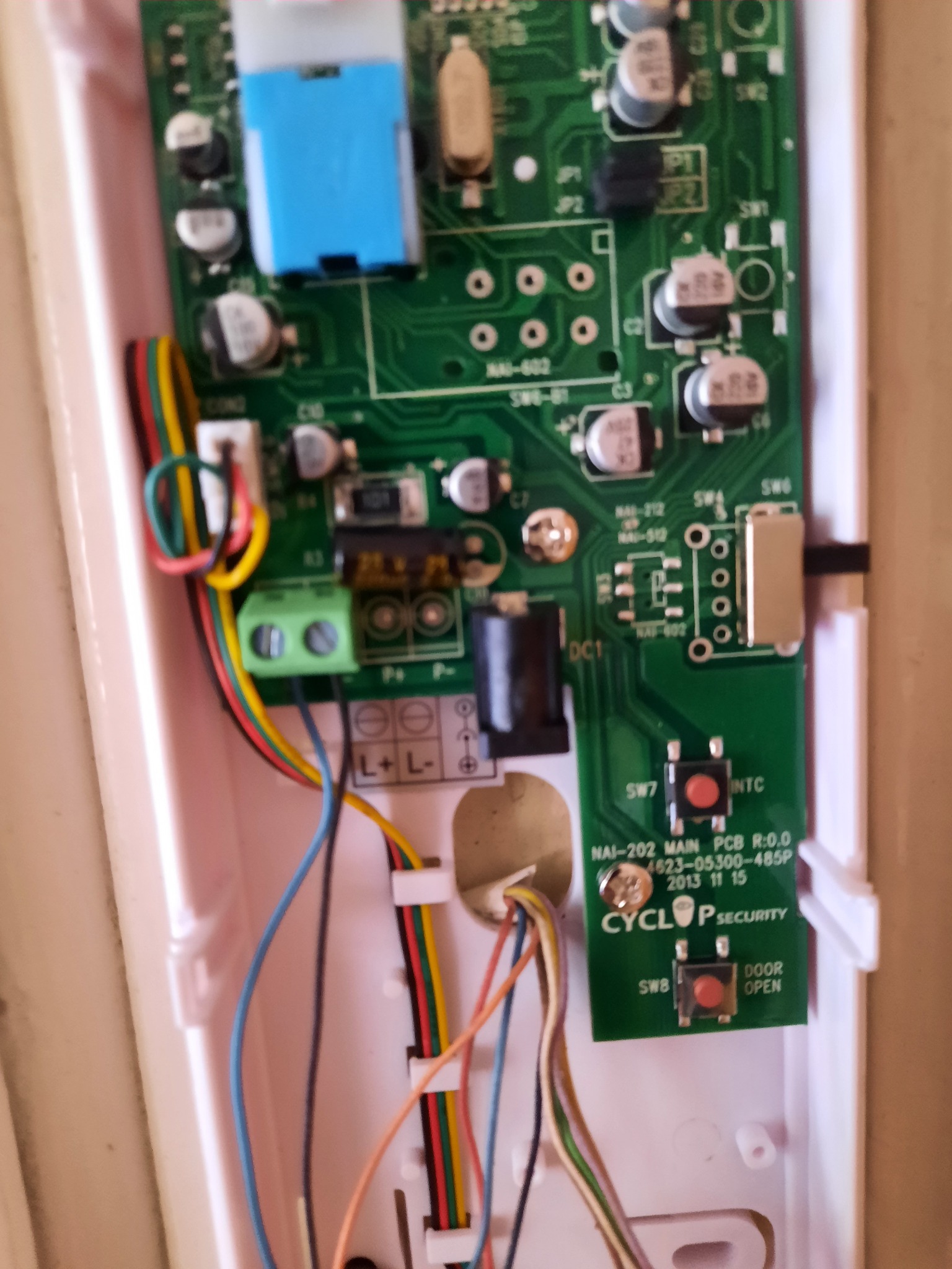 Otwarta obudowa wideodomofonu z widoczną elektroniką, płytką PCB z elementami i podłączonymi kablami, przyciski otwierania drzwi i logo Cyclop Security.