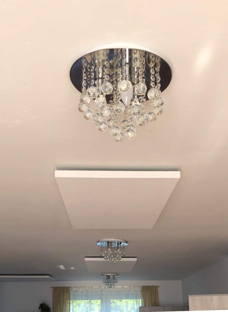 Kryształowy żyrandol sufitowy zamontowany w mieszkaniu w Warszawie, widok z dołu na dwa podobne oświetlenia i panele sufitowe.