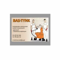Ilustracja przedstawiająca dwóch mężczyzn w kombinezonach roboczych, stojących obok pomarańczowej maszyny do nakładania tynków, na tle ściany z cegieł, logo firmy BAS-TYNK oraz dane kontaktowe.