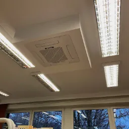 Sufit z zamontowaną kasetonową klimatyzacją Gree i oświetleniem rastrowym, widok od dołu.