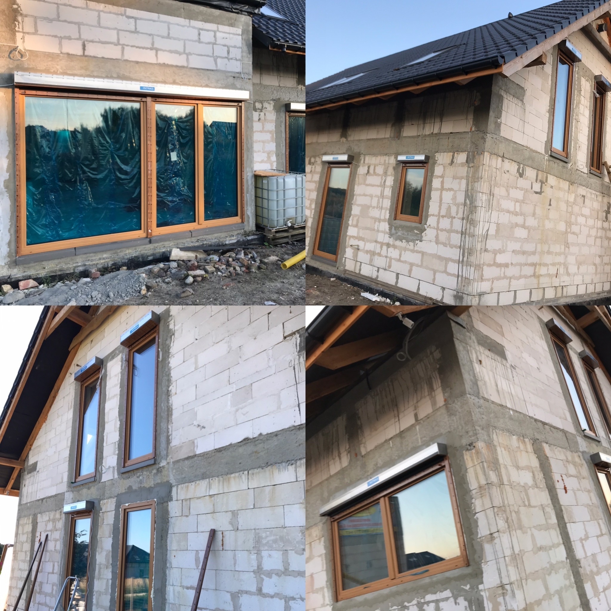 Budynek w trakcie budowy z zamontowanymi oknami z brązowymi ramami oraz roletami zewnętrznymi, widoczne zabezpieczenia folią na dużym oknie przesuwnym, białe bloczki betonowe i ślady zaprawy...