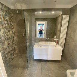 Margo sp.z.o.o - Nowoczesna łazienka z kabiną prysznicową wykończoną mozaiką kamienną, umywalką nablatową na białej szafce i dużym lustrem, w którym odbija się osoba robiąca zdjęcie.