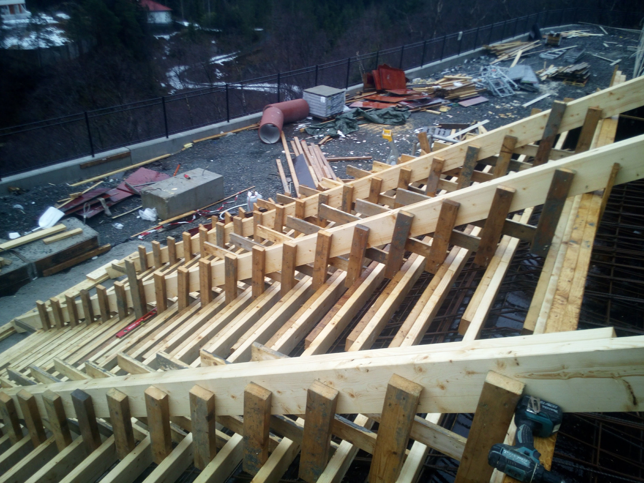 Szczegółowe ujęcie drewnianego szalunku zbrojenia fundamentów w Lipnie, z widocznymi narzędziami i elementami konstrukcyjnymi w tle.