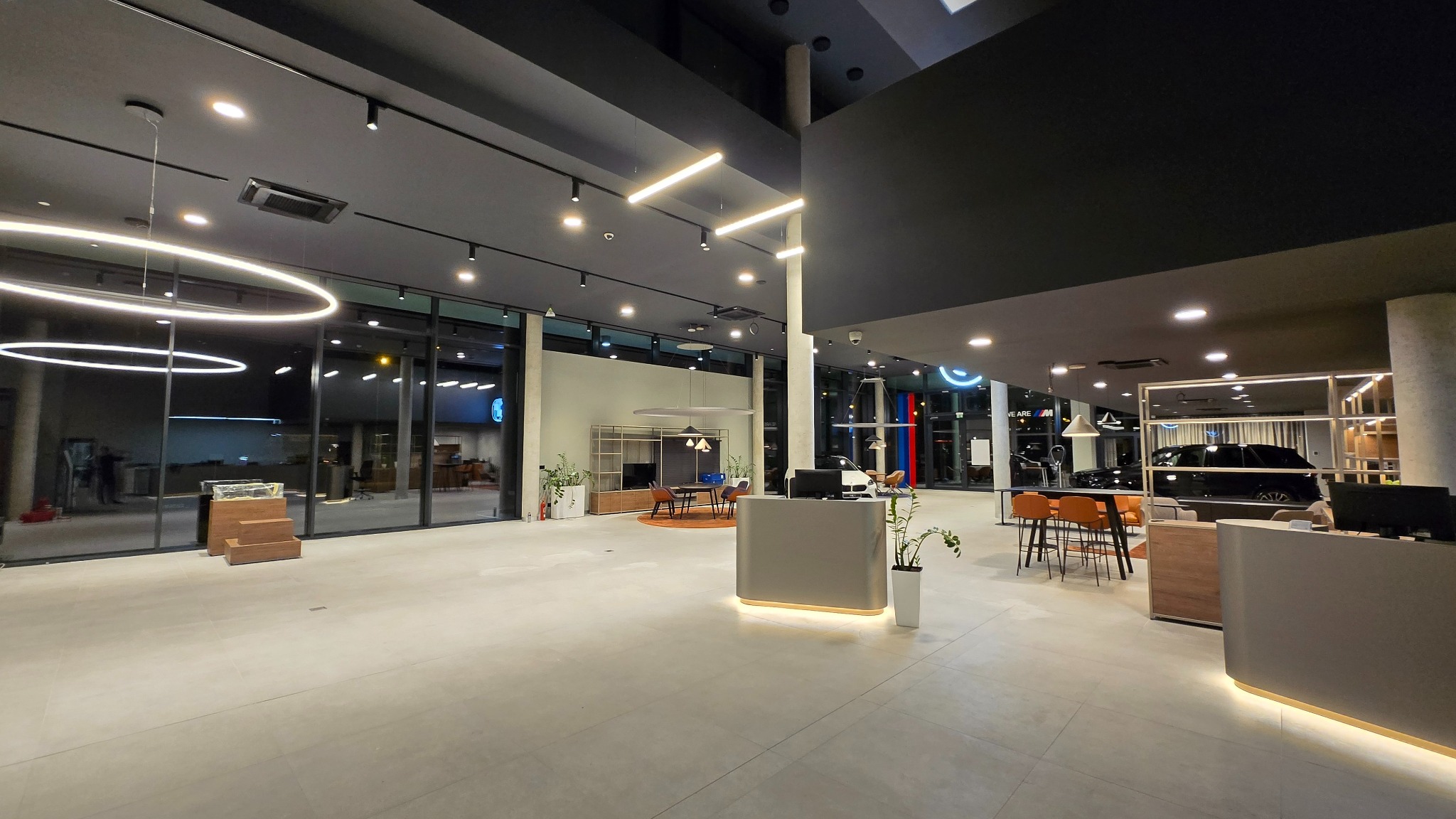 Nowoczesny salon samochodowy BMW po remoncie: minimalistyczny design, jasne oświetlenie, szklane witryny, recepcja z podświetleniem LED, eleganckie meble i ekspozycja aut.