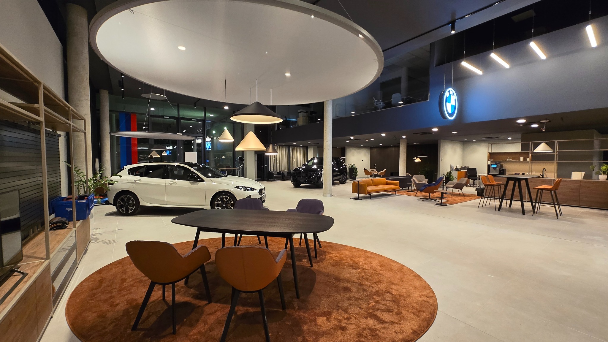 Salon samochodowy BMW po remoncie: jasne wnętrze z nowymi meblami, oświetleniem i ekspozycją aut. Widoczne auta, strefa klienta i logo BMW.