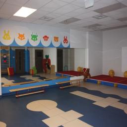 Sala gimnastyczna ze sceną teatralną, ścianą luster oraz drabinkami do ćwiczeń.   