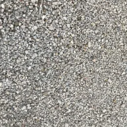 Drobny, szary kruszywo o zróżnicowanej granulacji, tworzące jednolitą powierzchnię, oświetlone naturalnym światłem.