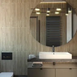 Nowoczesna łazienka z drewnopodobną okładziną ścienną, okrągłym lustrem z podświetleniem i ciemną marmurową podłogą. Minimalistyczna umywalka nablatowa z szafką i ręcznikami.