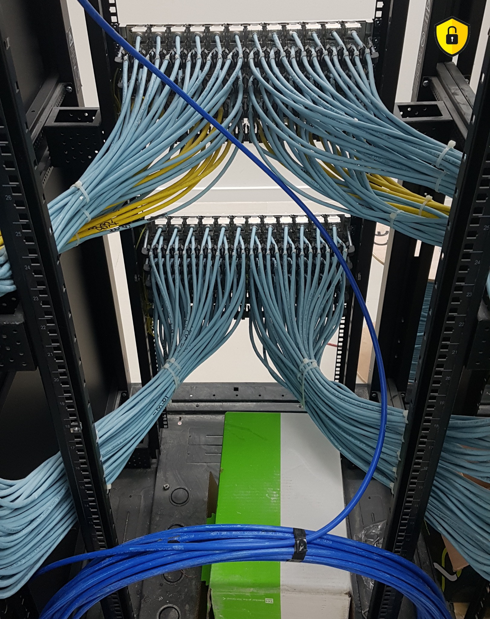 Rząd paneli krosowniczych w szafie rack z uporządkowanymi kablami Ethernet w kolorach niebieskim i żółtym, ze szczególnym uwzględnieniem numeracji na kablach.
