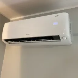 Biała jednostka wewnętrzna klimatyzatora Rotenso z wyświetlaną temperaturą 26 stopni Celsjusza, zamontowana na szarej ścianie w rogu pomieszczenia.