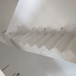 Sufit z nietypową, schodkową konstrukcją, przygotowany do wykończenia, widoczne otwory pod oświetlenie, wstępnie wyszpachlowane łączenia.