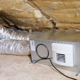 Centrala wentylacyjna z rekuperacją, zamontowana na poddaszu, widoczne srebrne rury wentylacyjne i izolacja stropu.