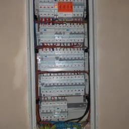 Rozdzielnica elektryczna w obudowie, widoczne zabezpieczenia SIMTEC, szyny montażowe, przewody w różnych kolorach oraz listwy zaciskowe.