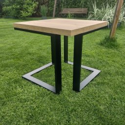 Emil Gradzik - Stół ogrodowy z drewnianym blatem i czarną, metalową podstawą w kształcie kwadratu, ustawiony na trawniku w Lubinie. W tle widoczny basen i huśtawka.