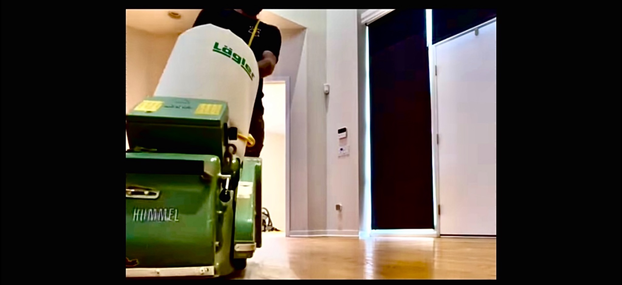 Praca cykliniarką Lagler Hummel na parkiecie w jasnym wnętrzu. Widoczny operator w czarnej koszulce. Podłoga po obróbce ma wysoki połysk.