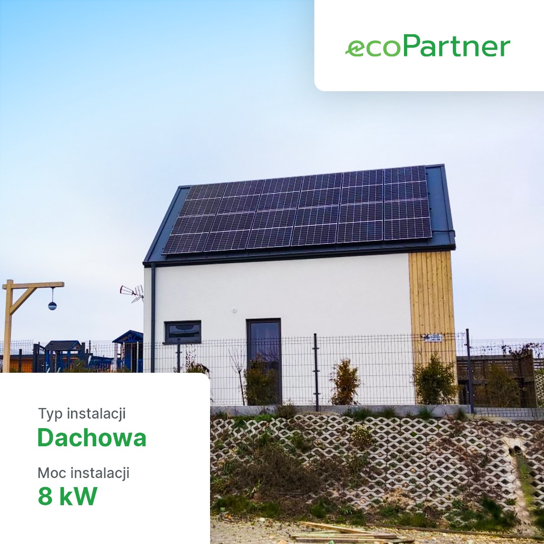 Niewielki dom jednorodzinny z panelami słonecznymi na dachu, instalacja dachowa o mocy 8 kW, widoczny znak ecoPartner w prawym górnym rogu.