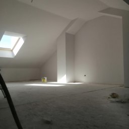 Andrzej skorupski - Poddasze po świeżym malowaniu na biało, widoczne okno dachowe wpuszczające światło, resztki farby na podłodze i fragment drabiny malarskiej.