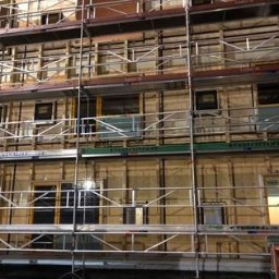 Andrzej skorupski - Elewacja budynku w trakcie ocieplania, widoczne rusztowania i warstwy izolacyjne przed montażem elewacji zewnętrznej.