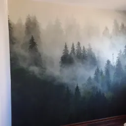 Fototapeta z motywem mglistego lasu iglastego na ścianie w rogu pokoju, widoczny fragment okna i podłogi z paneli.