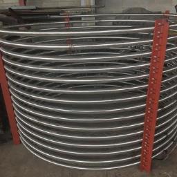 Niko-force sp. z o.o. - Spiralna rura ze stali nierdzewnej, podparta czerwonymi profilami, widoczna w warsztacie.