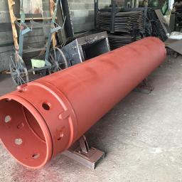 Niko-force sp. z o.o. - Czerwony, pomalowany walec metalowy z otworami, umieszczony na metalowych wspornikach w warsztacie.