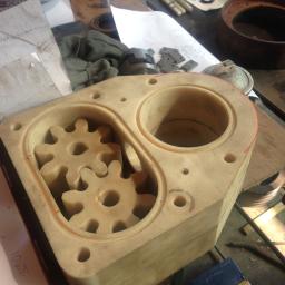 Niko-force sp. z o.o. - Beżowy blok z tworzywa sztucznego z wyfrezowanymi dwoma komorami, w jednej z nich umieszczone dwa koła zębate. W tle widoczne narzędzia i notatki.