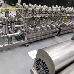 Spaw System Weldnig Group - Kompleksowa instalacja przemysłowa ze stali nierdzewnej z licznymi zaworami, rurami i przewodami, widoczne elementy automatyki i dokumentacja techniczna obok.