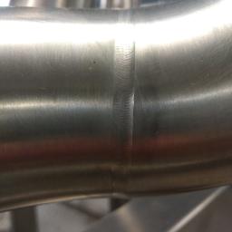 Spaw System Weldnig Group - Szczegółowe zbliżenie na spawany szew dwóch rur ze stali nierdzewnej, widoczne ślady obróbki