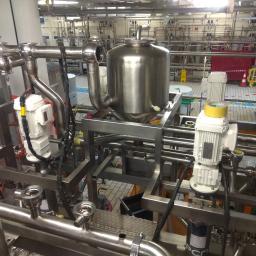 Spaw System Weldnig Group - Kompleksowa instalacja przemysłowa ze stali nierdzewnej, z widocznymi silnikami elektrycznymi, zbiornikiem ciśnieniowym i licznymi rurami oraz zaworami w hali produkcyjnej.