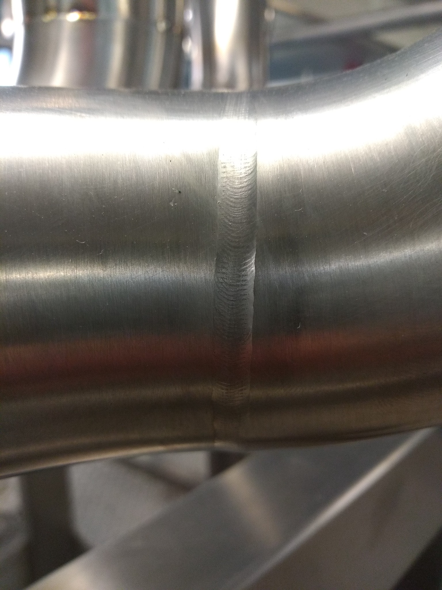 Szczegółowe zbliżenie na spawany szew dwóch rur ze stali nierdzewnej, widoczne ślady obróbki