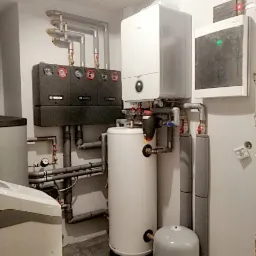 Zestaw urządzeń w kotłowni: kondensacyjny kocioł gazowy, zasobnik ciepłej wody, grupa pompowa Bosch z trzema obiegami grzewczymi oraz naczynie przeponowe.