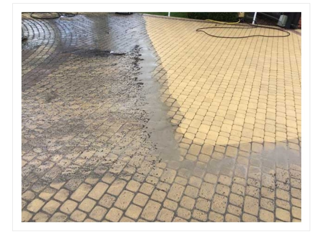 Częściowo wyczyszczona kostka brukowa na podjeździe, widoczna różnica między brudną a czystą powierzchnią, woda z mycia ciśnieniowego.