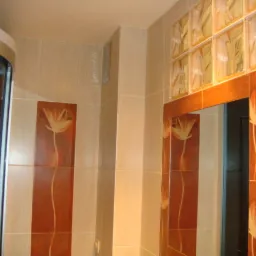 Wykończona łazienka z kabiną prysznicową, dekoracyjnymi panelami z motywem kwiatowym i luksferami nad lustrem.