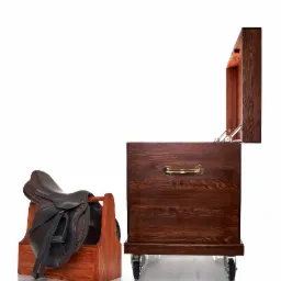 Ręcznie wykonana, lakierowana skrzynia z drewna z uchwytem i kółkami, obok stojak z brązowym skórzanym siodłem jeździeckim.