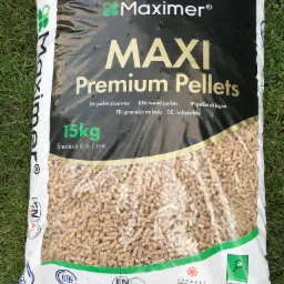 Worek 15 kg z pelletem drzewnym marki Maximer, leżący na trawie, z widocznymi certyfikatami jakości ENplus A1 i DINplus.