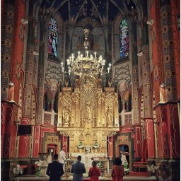 M.W.FotoPasja - Wnętrze bogato zdobionego kościoła podczas ceremonii, z ołtarzem w złocie i wiernymi w ławkach, widoczne witraże i malowidła na sklepieniu.